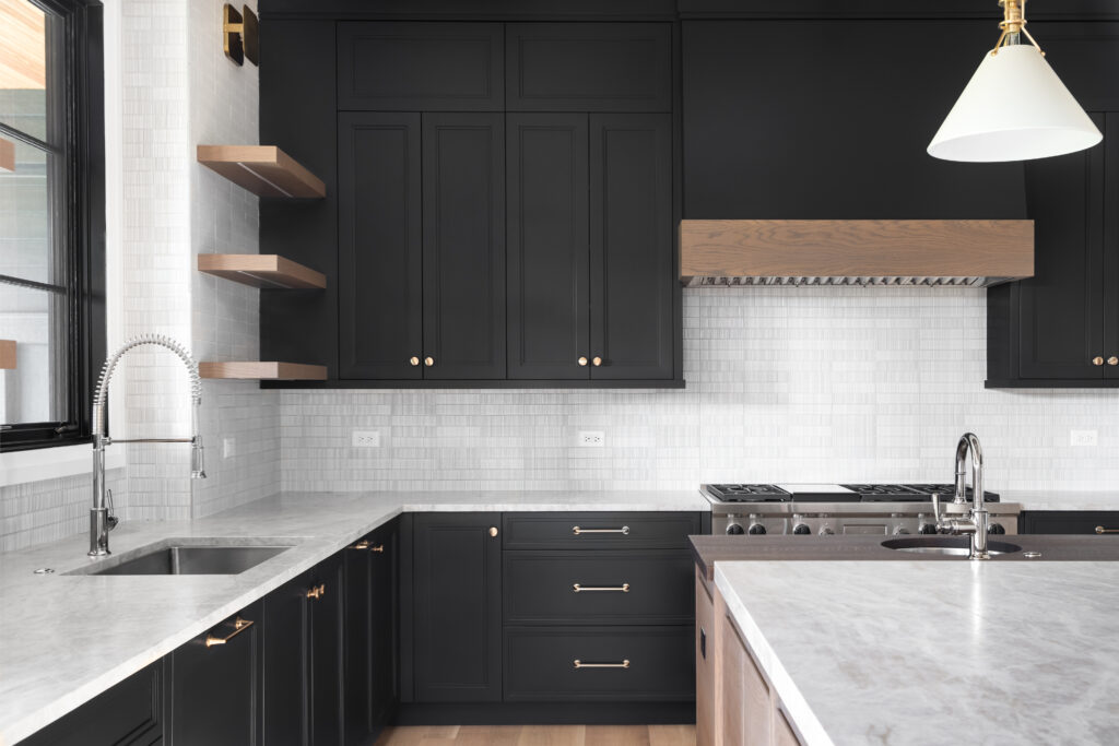 black cabinets, granite counter top, tiled backsplash, stainless steel appliances, and chrome faucets.