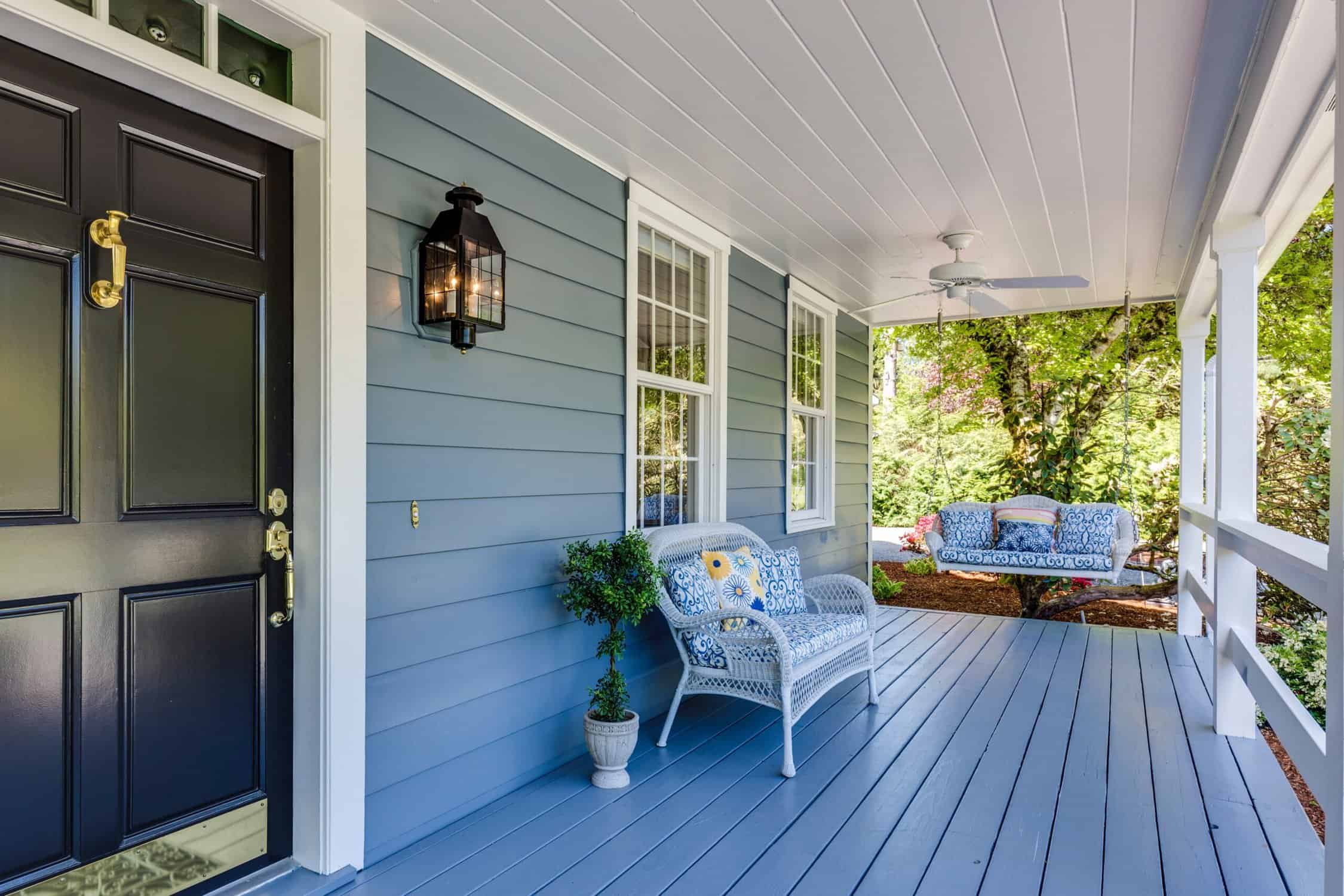 front porch painted in light blue and white with black door, with accent chair and hammock